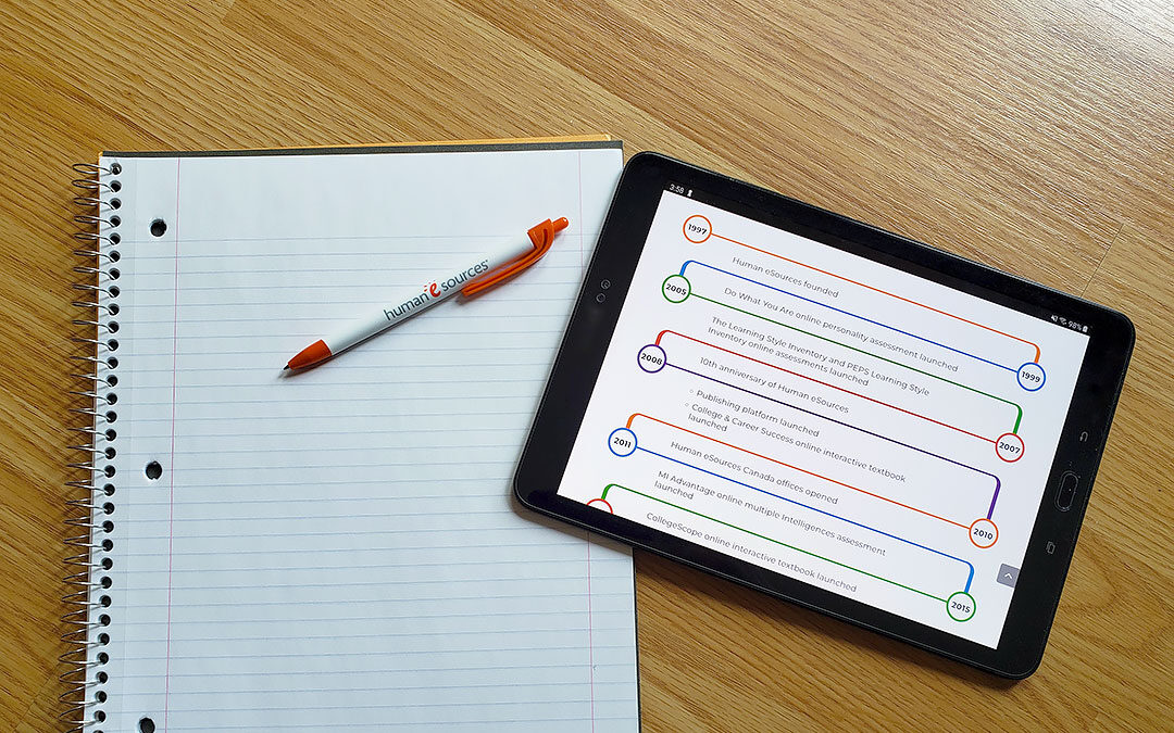 Pen and paper with tablet displaying timeline